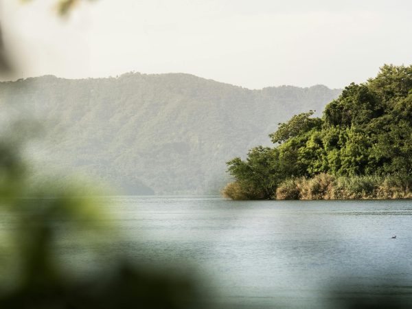 A tranquil scene of a lake surrounded by lush mountains in El Salvador, captured at dawn.