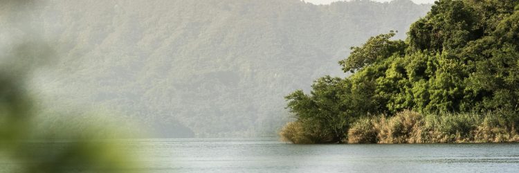 Una escena tranquila de un lago rodeado de exuberantes montañas en El Salvador, capturado al amanecer.
